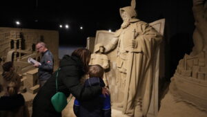 Moeder en kind kijken vol verbazing naar zandsculptuur