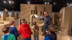 Kinderen kijken bij opbouw zandsculpturen thema boeken